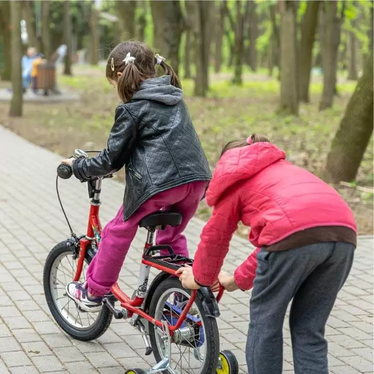 ילדה עוזרת לילדה על אופניים